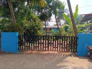 a black fence with blue doors and trees at Sheshatara Homestay in Honāvar