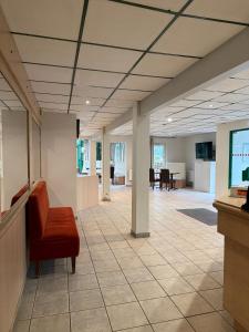 an empty office lobby with a chair and tables at Mot Hotel in Claye-Souilly