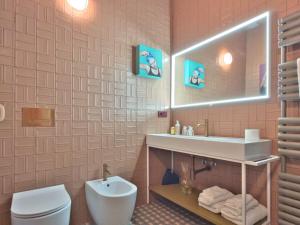 a bathroom with a sink and a toilet and a mirror at Homeby, Cinisca Suite Rose in Bologna