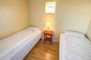 two beds in a room with a table and a window at Fossatún Sunset Cottage in Fossatún