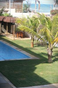 a resort with a palm tree and a swimming pool at Pousada Maresia in Guajiru
