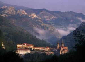 a large building with a mountain range at Arcea Gran Hotel Pelayo in Covadonga