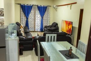 a living room with couches and blue curtains at Green Hill Stay in Fort Portal