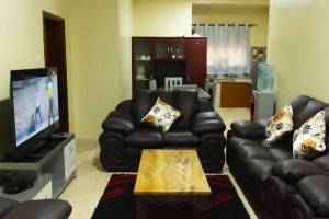 a living room with black leather couches and a tv at Green Hill Stay in Fort Portal