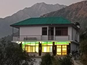 a house with a green roof on a mountain at Amazing view Home Stay in McLeod Ganj