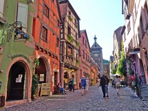 a group of people walking down a cobblestone street at Chez Famille RENTZ in Riquewihr