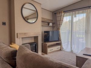 a living room with a couch and a tv and a mirror at Oakmont Lodge in Allerthorpe