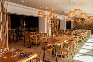 a restaurant with wooden tables and chairs and chandeliers at CAMPING & SPA CAP SOLEIL in Vias