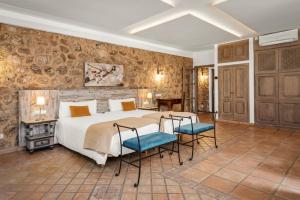 a bedroom with a large bed and two chairs at Finca Binibona Parc Natural in Binibona