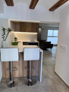 a kitchen with two white bar stools in a room at Centro Histórico - Beneficencia Flat in Valencia