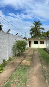 a road leading to a white house with a wall at Flat casa de madeira in São José da Coroa Grande