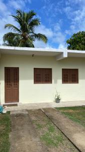a white house with brown doors and a palm tree at Flat casa de madeira in São José da Coroa Grande +14 photos