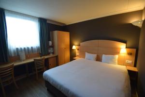 a hotel room with a large bed and a desk at DC Sleep & Go Brussels West in Brussels +23 photos