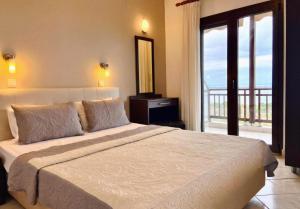 a bedroom with a large bed and a balcony at THEA Panorama Studios in Vourvourou