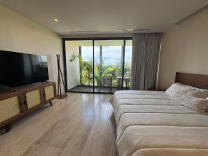 a hotel room with a bed and a flat screen tv at Alof Studio in the Jungle in Tulum +28 photos