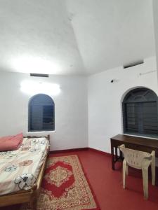 a bedroom with a bed and a table and two windows at Westernmagic in Idukki