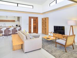 sala de estar con sofá, TV y mesa en Corail Bleu Private Villas by LOV en Bain Boeuf