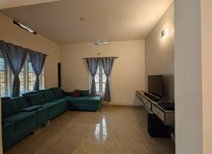 a living room with a green couch and a television at Sintra Villa in Meppādi