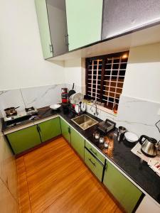 a kitchen with green cabinets and a wooden floor at hello 6 cliff stay varkalacliff - cozy rooms , couple friendly ,family ,group rooms in Varkala
