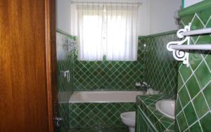 a green tiled bathroom with a tub and a sink at Gîte dans les vignes la calade in Grimaud