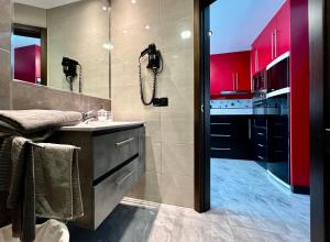 a bathroom with a sink and a shower with red cabinets at Atlantic Green 3 Apartment, Terrace, Solarium and Spa in El Cotillo +35 photos
