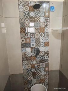a bathroom with a tiled wall with a toilet at Sri Madapallii in Tiruchirappalli