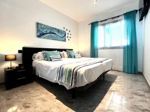 a bedroom with a large bed with blue curtains at Atlantic Green 3 Apartment, Terrace, Solarium and Spa in El Cotillo
