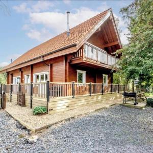 a log home with a deck and a house at Alpine Lodge in Pentney