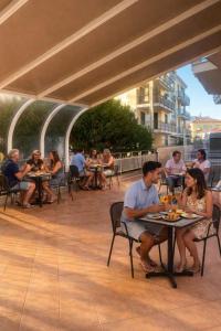 a group of people sitting at tables on a patio at Hotel SoleMare in Diano Marina