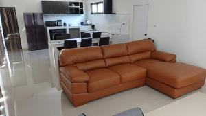 a brown couch in a living room with a kitchen at Villa Kitima homestay in Ban Chat