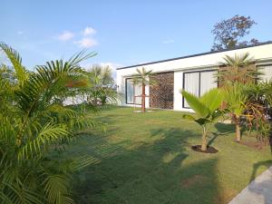 a garden with palm trees and a house at Villa Kitima homestay in Ban Chat