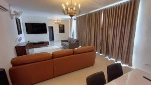 a living room with a brown couch and a television at Villa Kitima homestay in Ban Chat