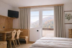 a bedroom with a bed and a desk and a window at Sporting Aparthotel in San Martino di Castrozza +23 photos