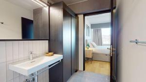 a bathroom with a sink and a room with a bed at Alto-Tower Residence - Self Check In in Zurich