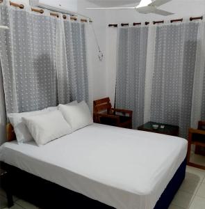 a bedroom with a bed with white sheets and curtains at Hotel Ningo in Santa Bárbara de Samaná