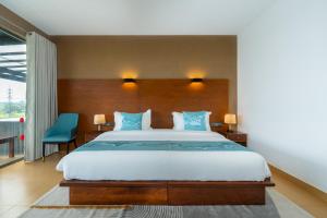 a bedroom with a large bed with blue pillows at Trio Lodge- Habarana in Habarana