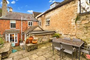 a patio with a table and chairs next to a building at Finest Retreats - Aarons in Painswick