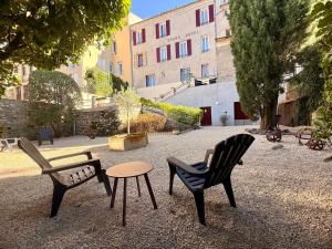 two chairs and a table in front of a building at Le Grand Hotel in Forcalquier