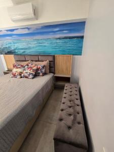 a bedroom with a bed with a painting of the ocean at Casa Nova Marilea in Rio das Ostras