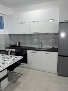 a kitchen with white cabinets and a sink and a table at Sun Stay in Bar
