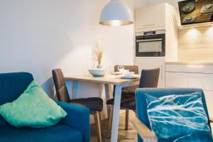 a kitchen with a table with chairs and a blue couch at Am Park 13 in Prerow