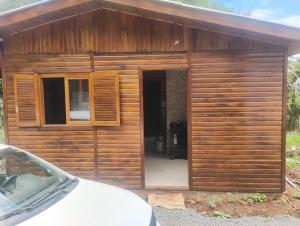 a small wooden shed with a door and a car at Casa de Temporada BR 470 in Cafundó