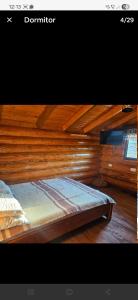 a bed in a room with a wooden wall at Căbănuțe lemn cu ciubăr in Varvata +36 photos