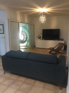 a living room with a blue couch and a tv at Chic, bright and quiet in Baie-Mahault