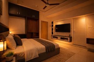 a bedroom with a bed and a flat screen tv at DJ Imperial Suites in Trivandrum