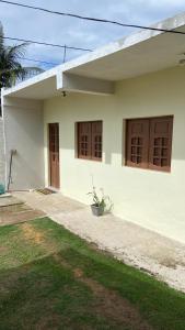 a white house with brown doors and a yard at Flat casa de madeira in São José da Coroa Grande