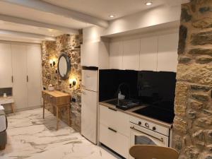 a kitchen with white cabinets and a stone wall at Castle View Serenity in Koroni