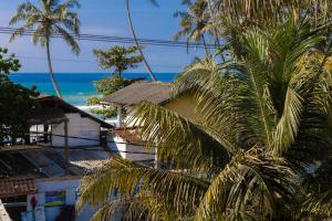 a house with a palm tree in front of the ocean at Beach House by Unrushed in Welhengoda