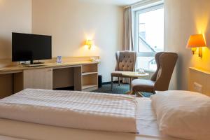 a hotel room with a bed and a desk with a television at Trip Inn Hotel Astoria in Göttingen +84 photos