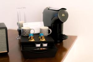 a desk with a coffee maker and two coffee cups at Kymo Fig Tree Bay House in Protaras